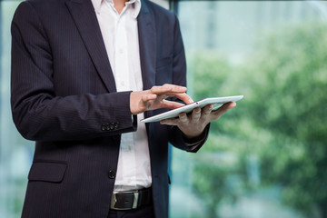 Close up image of business man holding a digital tablet,Portrait of handsome young man working with tablet in the office.Intelligent and confidents businessman holding touch pad with infographics