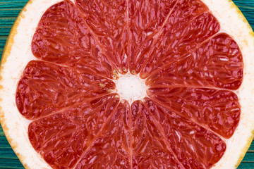 Fresh half cut grapefruit on a blue wooden background, close up view.