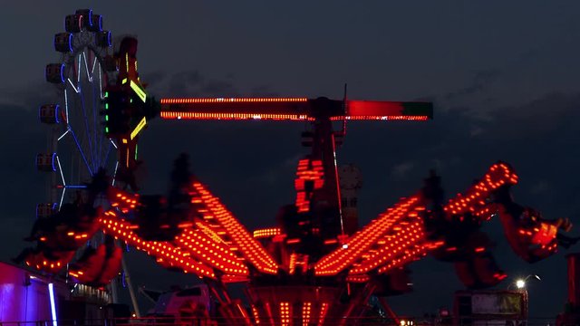 Attractions of fair, with colorful lights and moving at sunset.