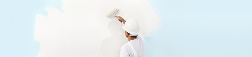 Rear view of painter man painting the wall, with paint roller, isolated on big empty space, web...