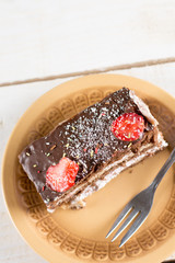 Slice of chocolate cake with fresh strawberries on the plate.