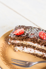 Slice of chocolate cake with fresh strawberries on the plate.