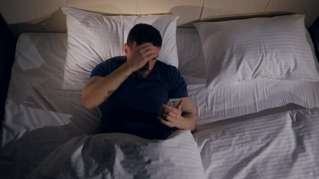 The man worrying about the information from the phone lying in the bed. 4K.