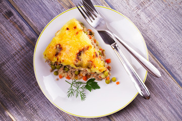 Meat, potato, cheese, carrot, onion and green peas casserole. Traditional shepherd pie. View from above, top studio shot