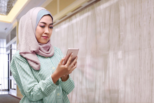 Beautiful asian woman with hijab holding smartphone