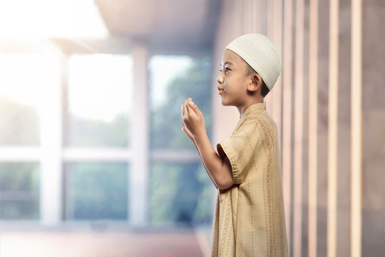 Portrait of asian muslim boy with white cap praying