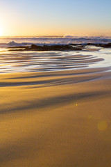 A placid early morning sunrise at Baggies Beach near Durban, South Africa.  Sunrise at the beach, showing a portrait view.