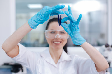 Smiling female scientist looking at test-tube