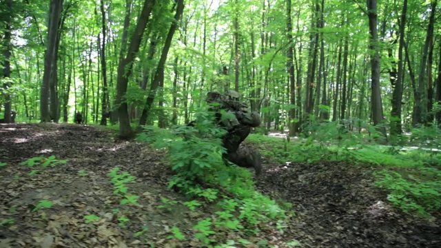 Guerilla partisan warrior aiming in forest ambush carrying his gun. Changing position maneuver. Relocation.