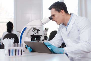 Confident brunette looking into microscope