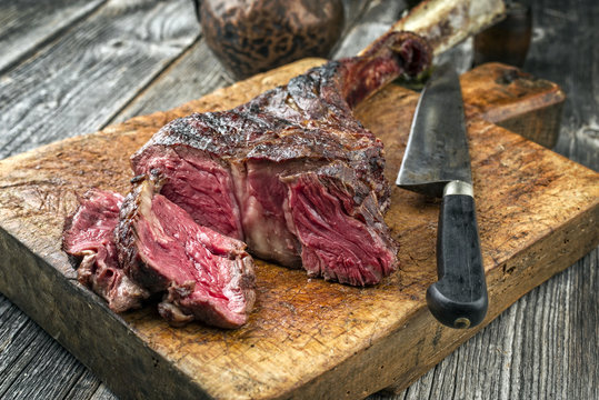 Barbecue dry aged Wagyu Tomahawk Steak sliced as close-up on an old cutting board