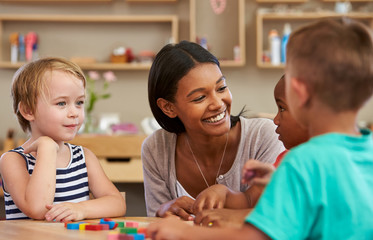 Teacher And Pupils Using Wooden Shapes In Montessori School