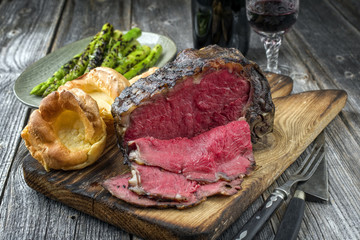 Barbecue dry aged Rib of Beef with green Asparagus and Yorkshire Pudding as close-up on an old...