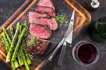 Barbecue Wagyu Point Steak with green Asparagus as close-up on burnt cutting board