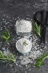 Sea salt scented herb rosemary on black stone background, natural light. Selective focus. 