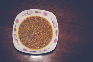orzo noodle soup in white bowl on wooden table