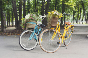 Fototapeta na wymiar Yellow and turqoise city woman bicycles with flowers in park