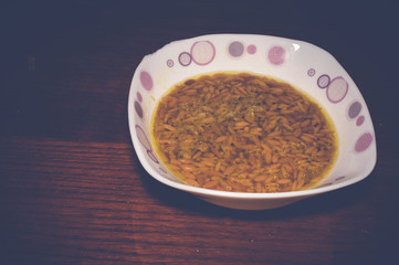 orzo noodle soup in white bowl on wooden table
