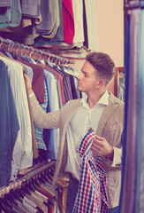 Male customer examining shirts in men’s cloths store