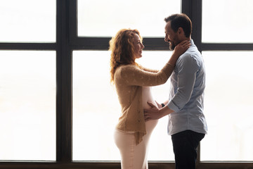 Married couple embracing over window background