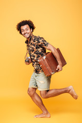 Young happy african man running with suitcase
