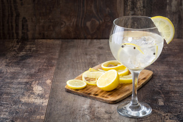 Glass of gin tonic with lemon on wooden background
