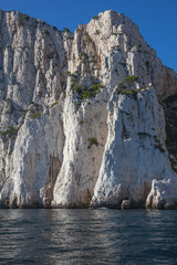 Fototapeta na wymiar Famous white limestone cliffs rising out of the water on blue sky background in Calanques national park near Cassis, France