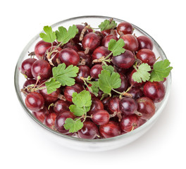 Red gooseberries with green leaves in glass bowl with clipping path