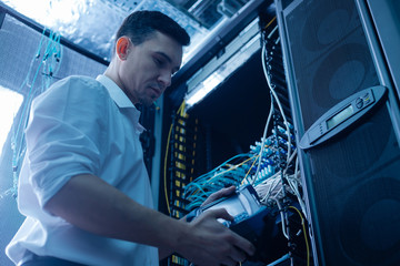 Handsome serious engineer working in the network server room