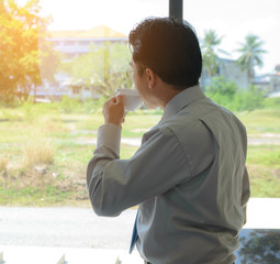 Businessman Standing window in office and drink Coffee