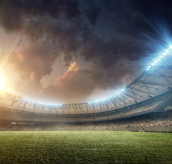 soccer stadium with illumination and green grass on sunset