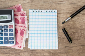 100 yuan with calculator and notepad, pen on desk.