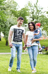 Fototapeta premium amily, parenthood, adoption and people concept - happy mother, father and little girl walking in summer park and having fun