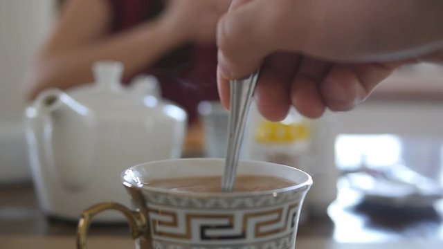 Male hand stirring sugar or milk in a cup of hot coffee or tea. Slow motion Close up