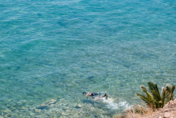 Blue sea, rocks, man swimming