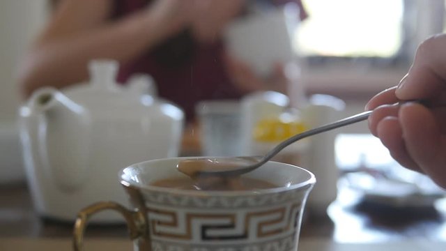 Female hand stirring sugar or milk in a cup of hot coffee or tea. Slow motion