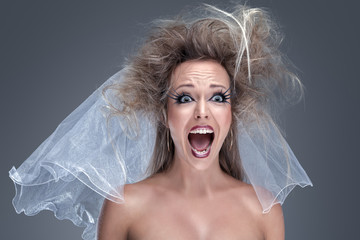 Angry screaming bride in wedding veil and creative makeup. Unhappy emotions.