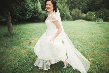Fototapeta premium Beautiful wedding bride running in the garden