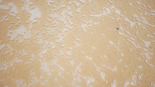 A top view of sand being splashed by waves at the beach