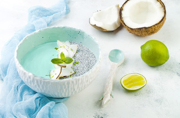Vegan blue spirulina smoothie and chia pudding bowl topped with coconut flakes and lime zest