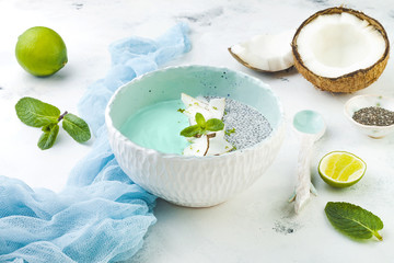 Obraz na płótnie Canvas Vegan blue spirulina smoothie and chia pudding bowl topped with coconut flakes and lime zest