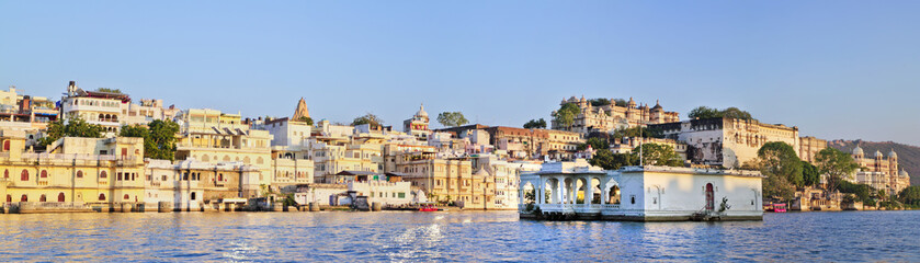 Fototapeta na wymiar Panoramic view of buildings on water and City Palace in Udaipur in India. View from Pichola Lake
