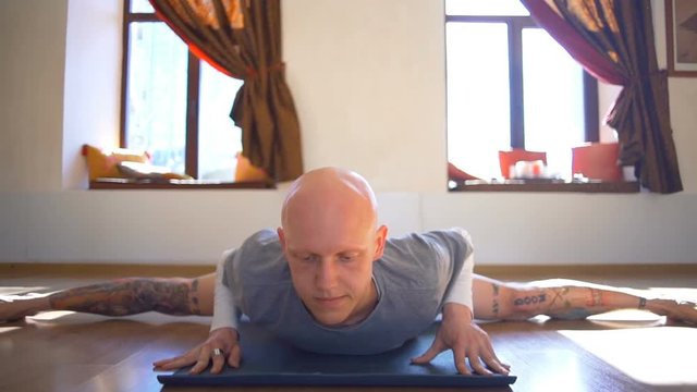 Man sits on the twine and then goes to the upward-facing dog pose slow motion