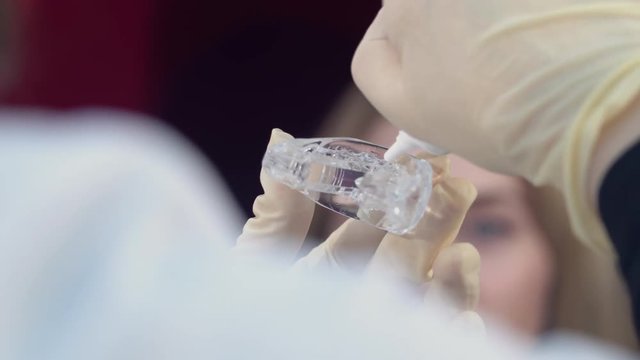 Preparation for teeth whitening for a young girl, puts gel on whitening trays.