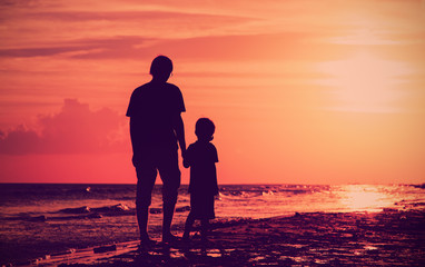 father and son walking at sunset sea