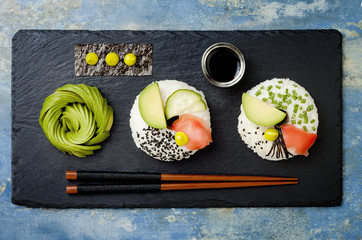 Vegan sushi donuts set with pickled ginger, avocado, cucumber, chives, nori and sesame served on stone slate. Sushi-food hybrids trend. Overhead, top view, flat lay.