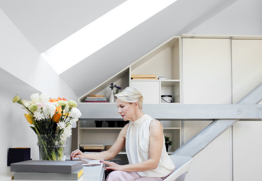 Beautiful elegant blonde senior businesswoman sitting in her office.