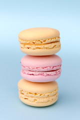 Three sweet colorful macaroons on blue table background.