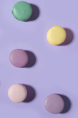 Sweet colorful macaroons on purple table background.