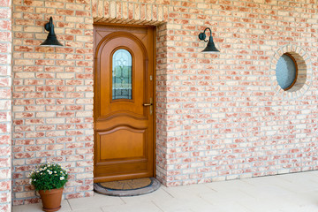 Fototapeta premium Stylish wooden front - entrance door in a detached house - embedded in a brick wall
